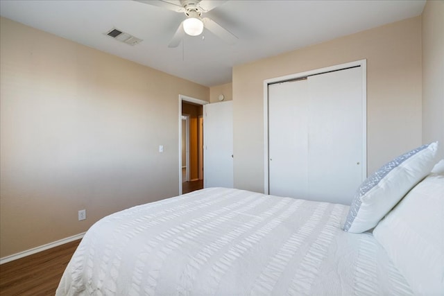 bedroom featuring dark wood finished floors, a closet, visible vents, ceiling fan, and baseboards