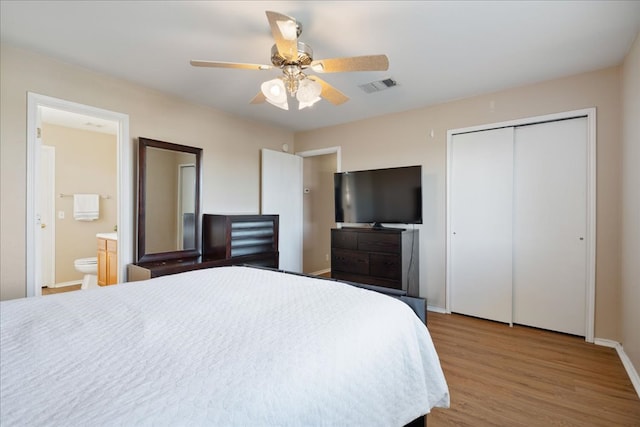 bedroom featuring baseboards, visible vents, ensuite bath, wood finished floors, and a closet