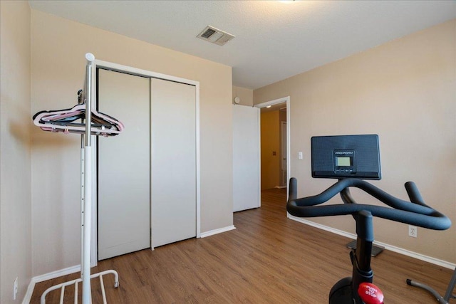 workout room with baseboards, visible vents, and wood finished floors