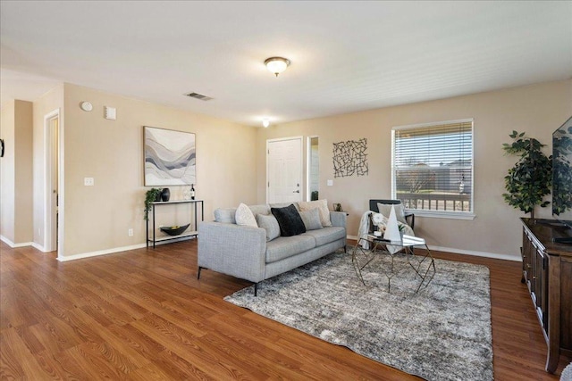 living area with visible vents, baseboards, and wood finished floors