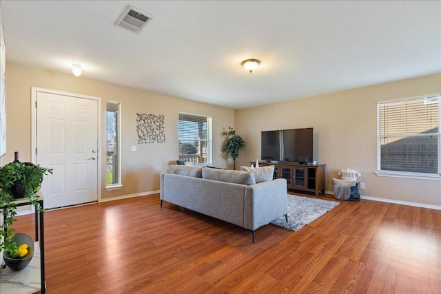 living area with light wood finished floors, visible vents, and baseboards