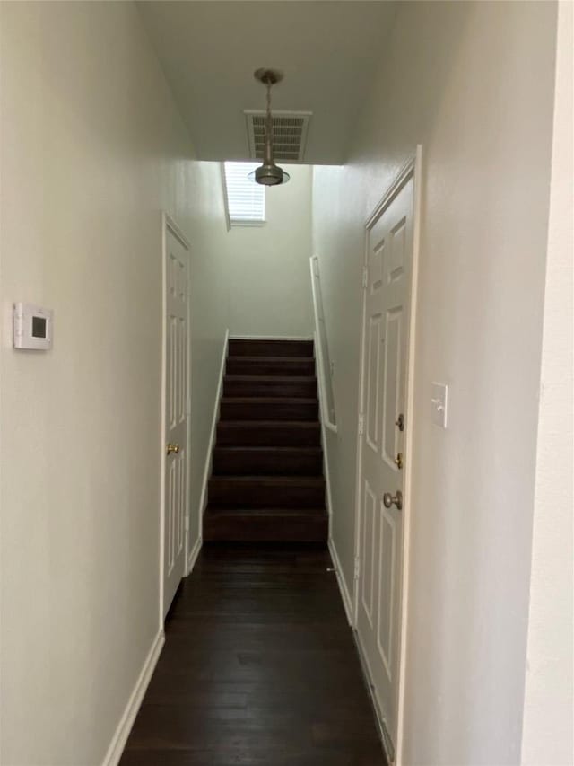 corridor with stairs, dark wood-style flooring, visible vents, and baseboards