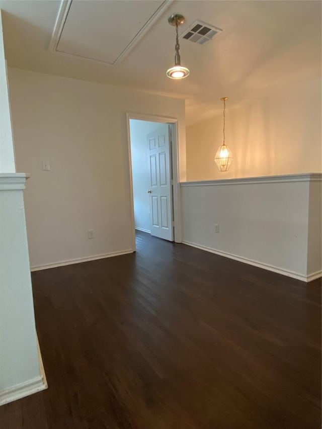 spare room with baseboards, attic access, visible vents, and dark wood-style flooring