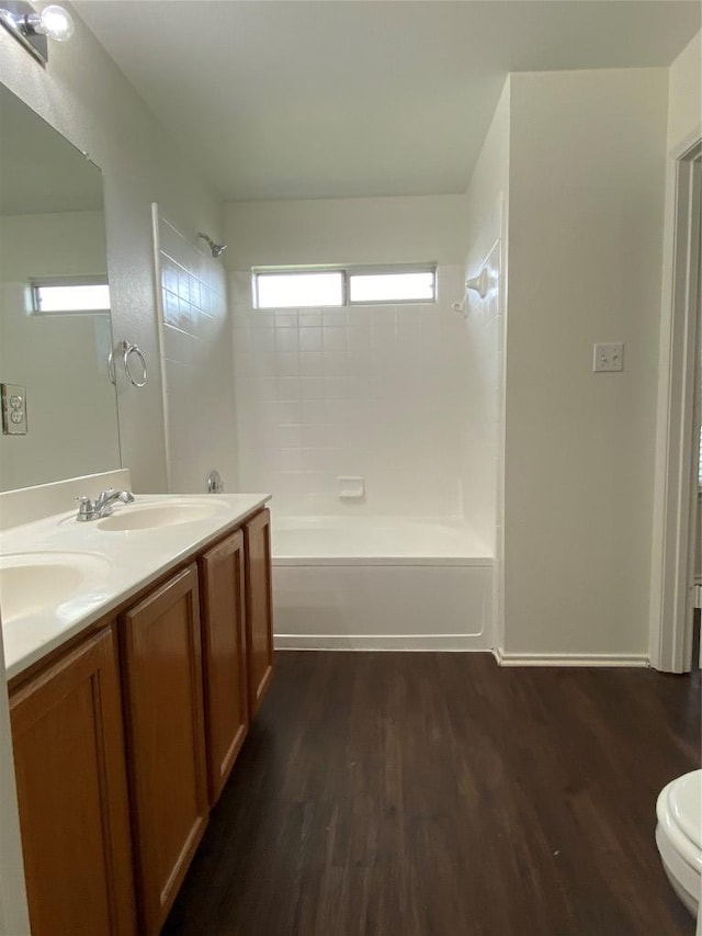 bathroom featuring double vanity, a sink, shower / tub combination, and wood finished floors