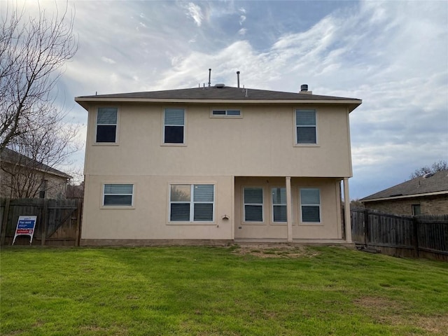 rear view of property featuring a fenced backyard, a yard, and stucco siding