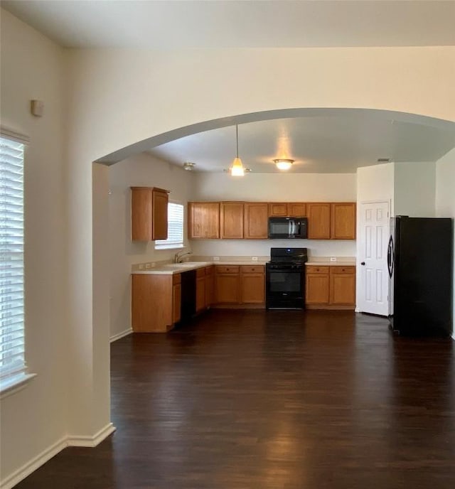 kitchen featuring dark wood-style floors, black appliances, light countertops, and baseboards