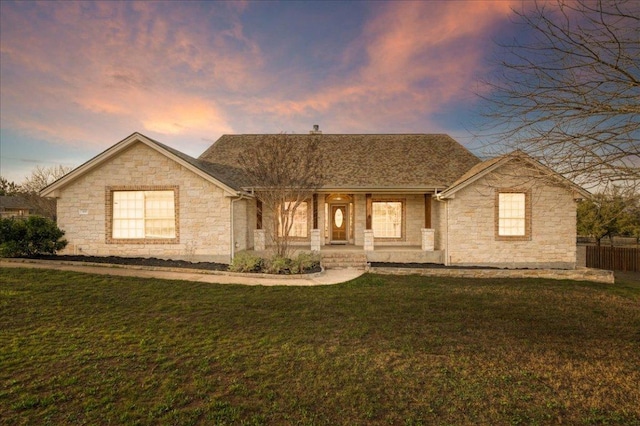 ranch-style house featuring covered porch, stone siding, a front lawn, and fence