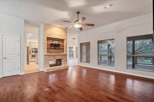 unfurnished living room featuring a fireplace, visible vents, baseboards, a ceiling fan, and hardwood / wood-style floors