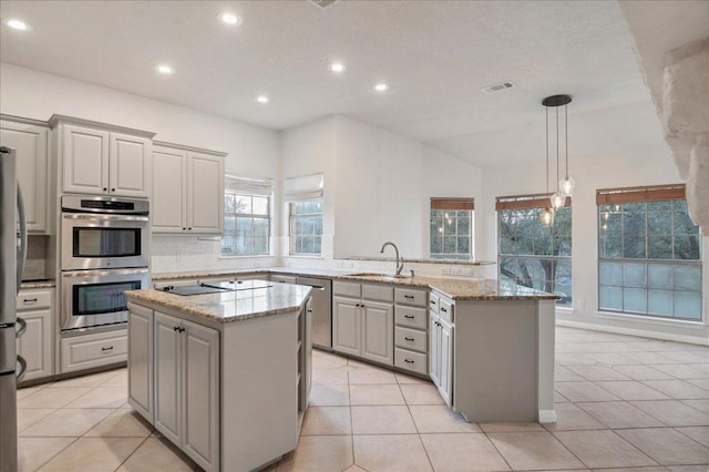 kitchen featuring decorative backsplash, appliances with stainless steel finishes, a peninsula, gray cabinets, and a sink