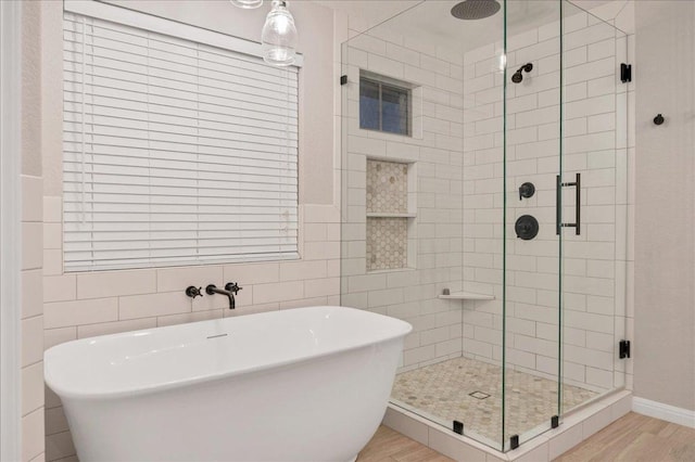 bathroom featuring wood finished floors, a soaking tub, and a shower stall