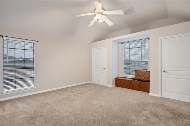 unfurnished bedroom featuring vaulted ceiling, light carpet, visible vents, and baseboards