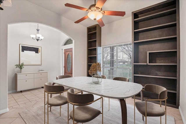 dining area featuring arched walkways, light tile patterned floors, a notable chandelier, baseboards, and built in features