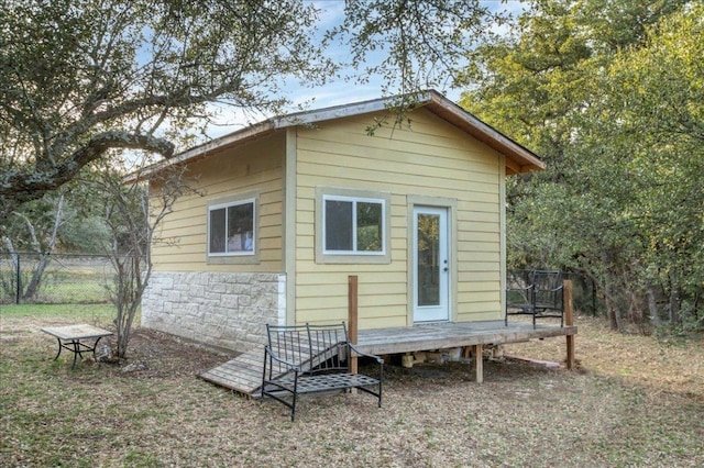 rear view of property with stone siding, fence, and a wooden deck