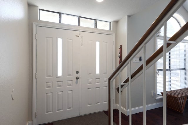 foyer with dark wood-type flooring, stairway, and baseboards