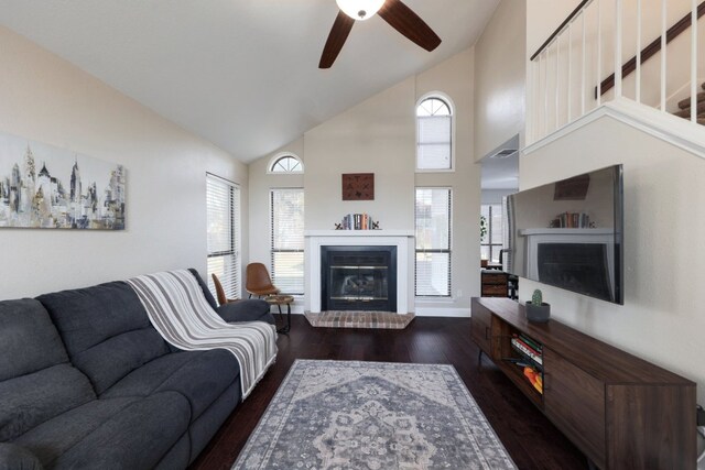 living area with a brick fireplace, dark wood-style floors, high vaulted ceiling, and ceiling fan