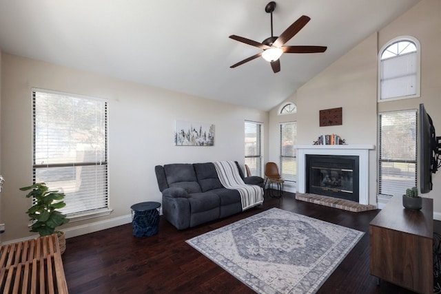 living room with ceiling fan, high vaulted ceiling, a brick fireplace, plenty of natural light, and dark wood finished floors