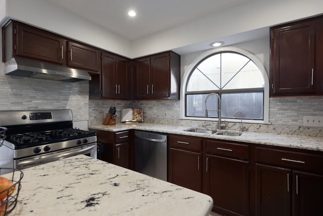 kitchen featuring under cabinet range hood, stainless steel appliances, a sink, dark brown cabinets, and light stone countertops