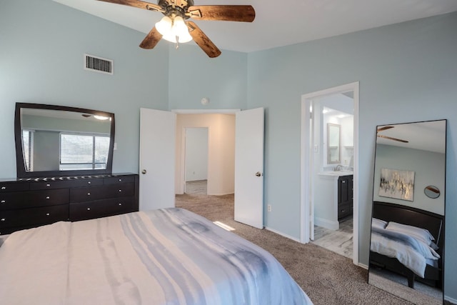 bedroom featuring visible vents, a ceiling fan, ensuite bathroom, carpet, and a high ceiling