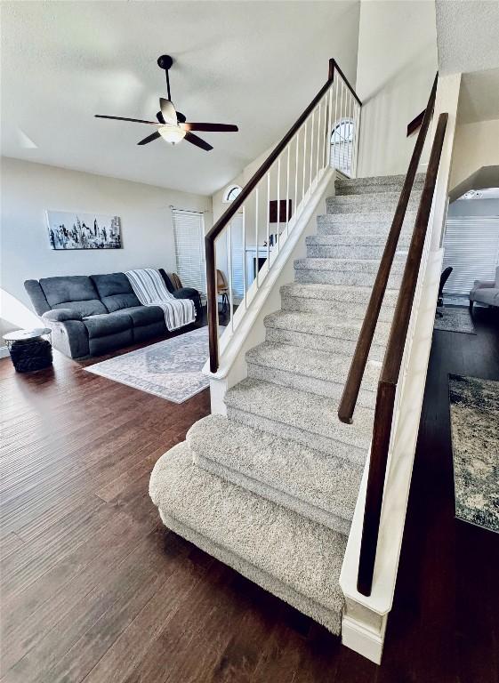 stairs featuring a ceiling fan and wood finished floors