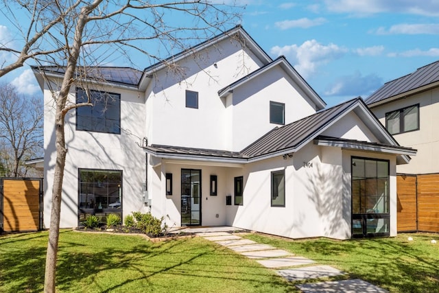 rear view of property with a standing seam roof, fence, metal roof, and stucco siding