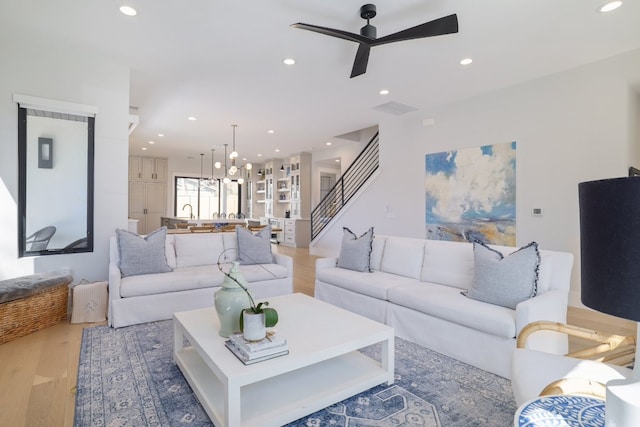 living area with stairs, light wood finished floors, and recessed lighting