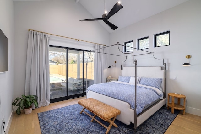 bedroom featuring baseboards, ceiling fan, wood finished floors, access to outside, and high vaulted ceiling