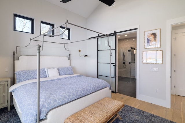 bedroom featuring vaulted ceiling, a barn door, wood finished floors, and baseboards