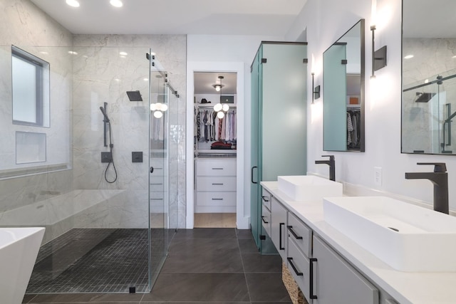 full bath with a spacious closet, double vanity, a stall shower, and a sink