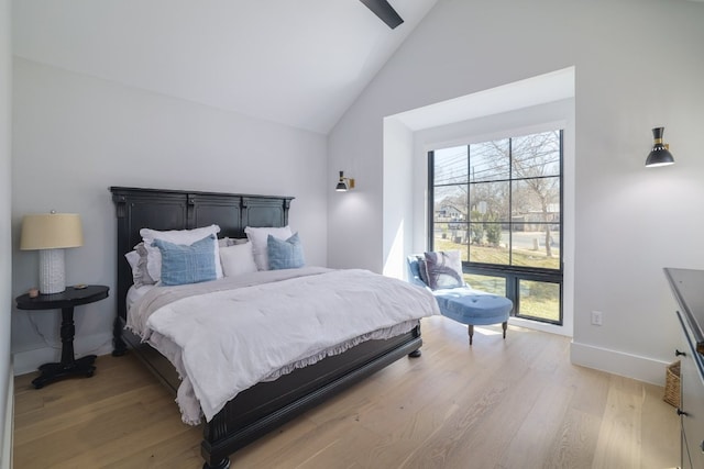 bedroom featuring vaulted ceiling, light wood-style flooring, and baseboards