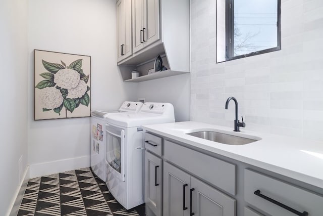 laundry area featuring cabinet space, baseboards, a sink, and washing machine and clothes dryer