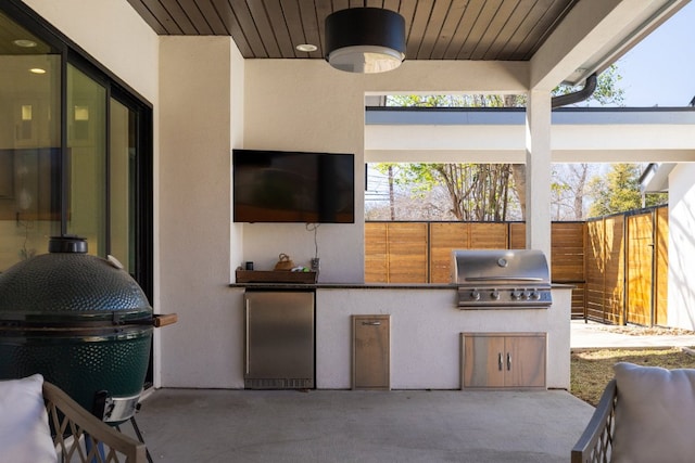 view of patio featuring ceiling fan, an outdoor kitchen, area for grilling, and fence