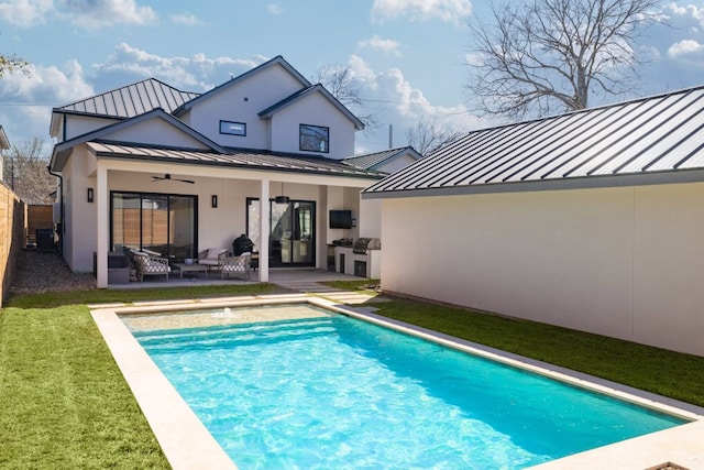 back of house with a ceiling fan, metal roof, a standing seam roof, exterior kitchen, and a patio area