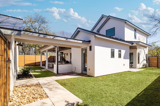 back of property with a lawn, a patio, metal roof, fence, and stucco siding