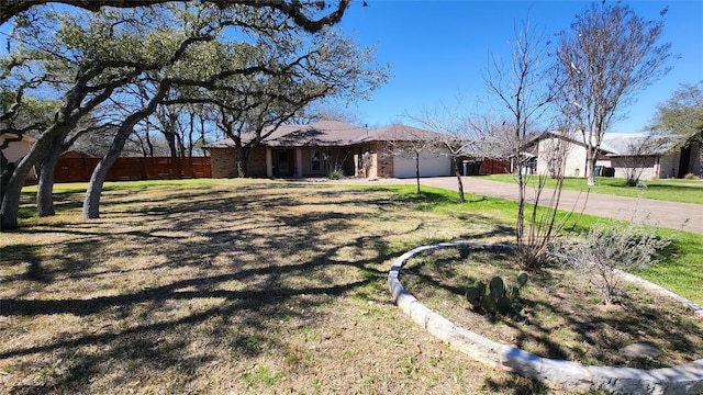 ranch-style home featuring a garage, driveway, and fence