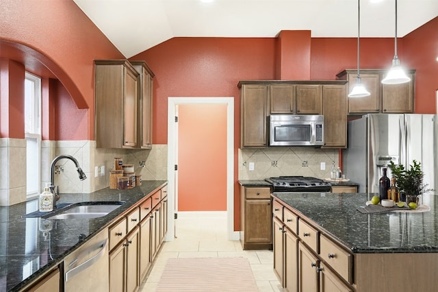 kitchen featuring lofted ceiling, light tile patterned floors, a sink, appliances with stainless steel finishes, and decorative light fixtures