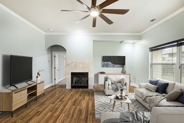 living room with crown molding, visible vents, wood finished floors, a tile fireplace, and baseboards