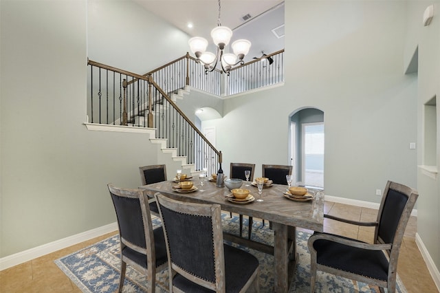 dining area with arched walkways, baseboards, stairway, tile patterned flooring, and a chandelier