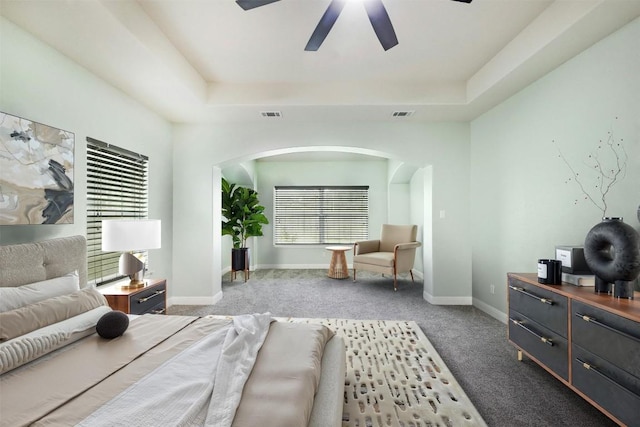 carpeted bedroom featuring ceiling fan, a raised ceiling, visible vents, and baseboards