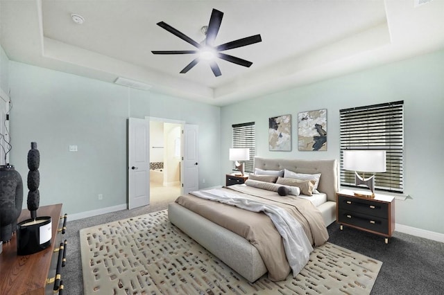 bedroom with carpet, a raised ceiling, baseboards, and ensuite bathroom