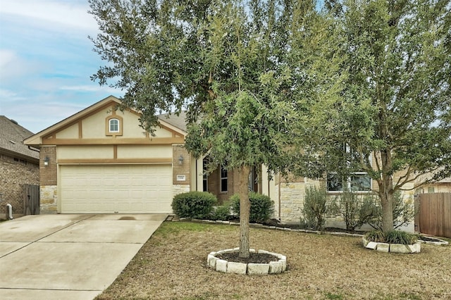 view of front of property featuring an attached garage, fence, stone siding, driveway, and stucco siding