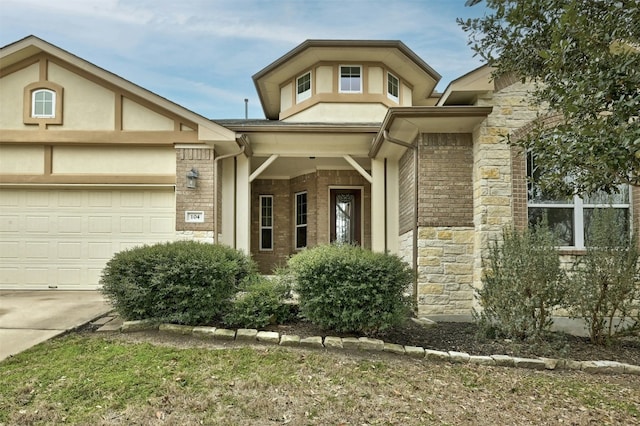 view of front of property featuring driveway, stone siding, an attached garage, and brick siding