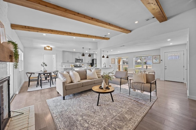 living area with plenty of natural light, light wood-type flooring, and beam ceiling