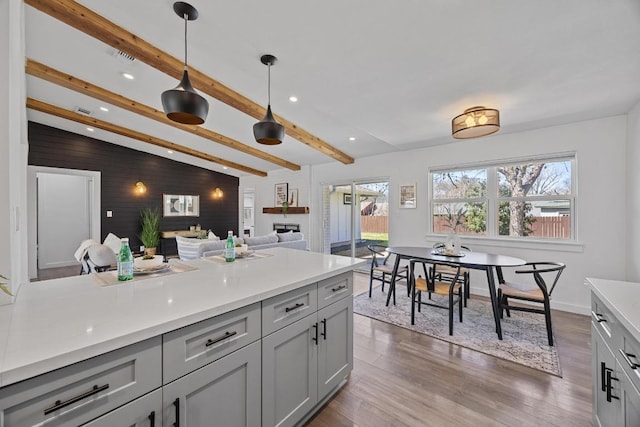 kitchen with decorative light fixtures, gray cabinets, light countertops, lofted ceiling with beams, and wood finished floors