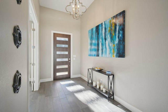 foyer featuring a notable chandelier, baseboards, and wood finished floors