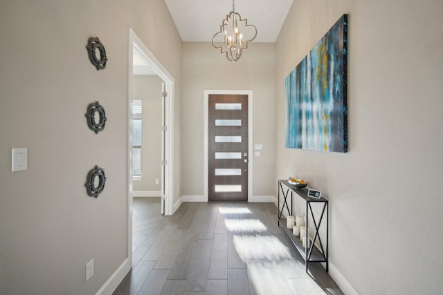 foyer featuring a chandelier, wood finished floors, and baseboards