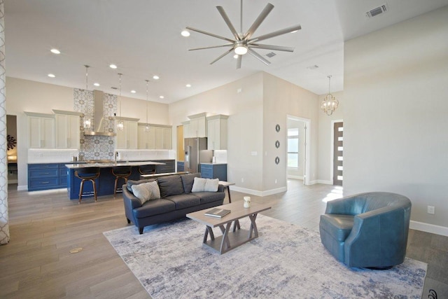 living area featuring baseboards, visible vents, wood finished floors, an inviting chandelier, and recessed lighting