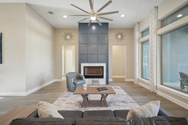 living room featuring visible vents, baseboards, a tiled fireplace, and wood finished floors