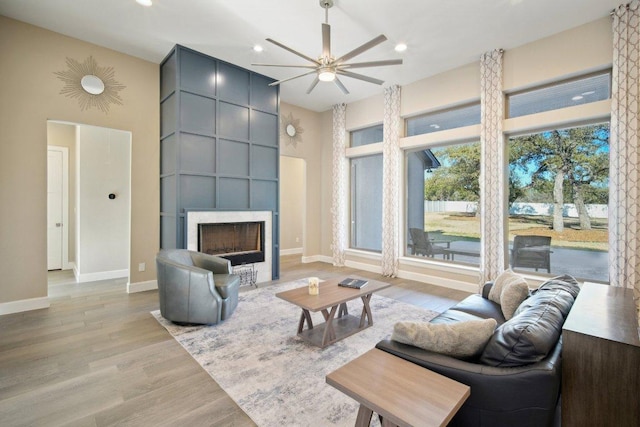 living room featuring light wood-type flooring, recessed lighting, a fireplace, and baseboards