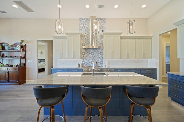 kitchen featuring light stone counters, visible vents, backsplash, white cabinets, and a kitchen bar