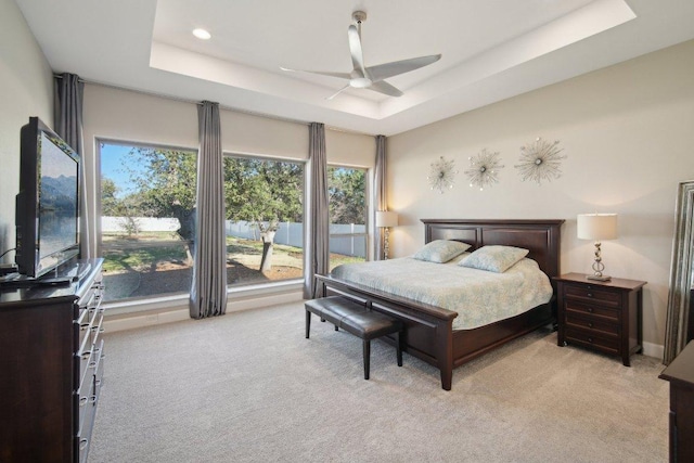 bedroom featuring a ceiling fan, a tray ceiling, light colored carpet, and recessed lighting